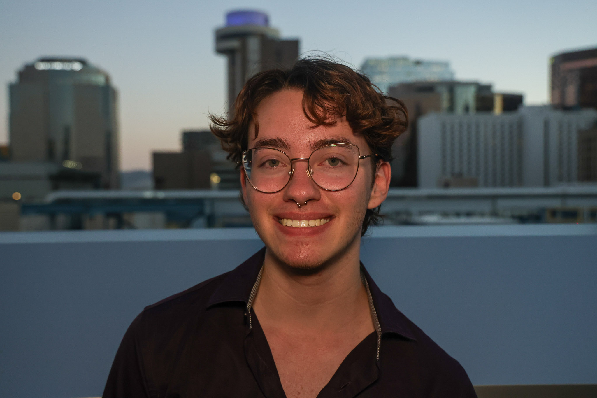 Jonah Manthey smiles in front of the downtown Phoenix cityscape.
